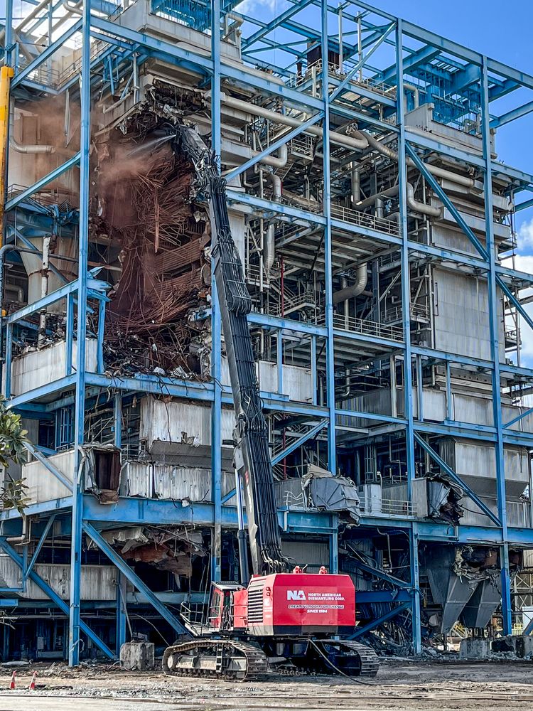 High-reach demolition machine dismantling a power plant boiler structure