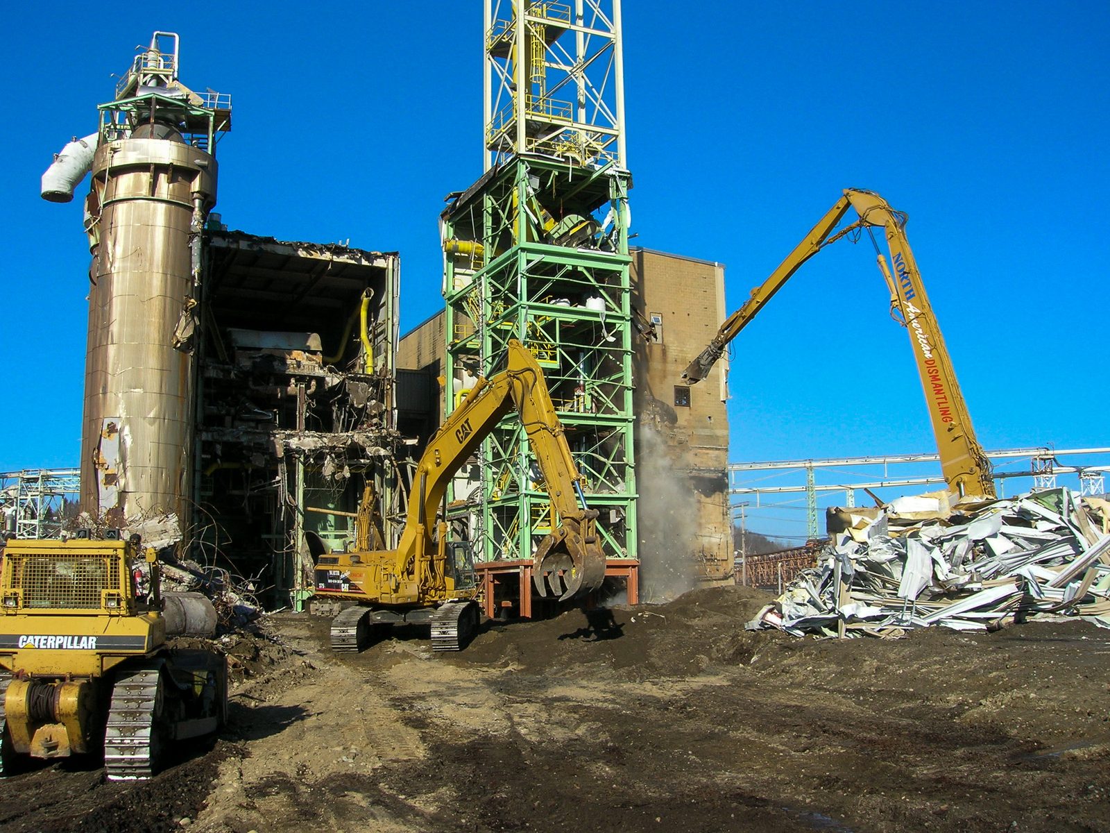 Excavator working between concrete stacks and silos at the Fraser pulp mill