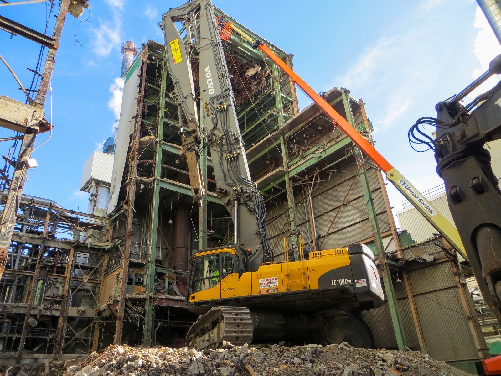 High-reach excavator dismantling a recovery boiler building inside the active P.H. Glatfelter paper mill