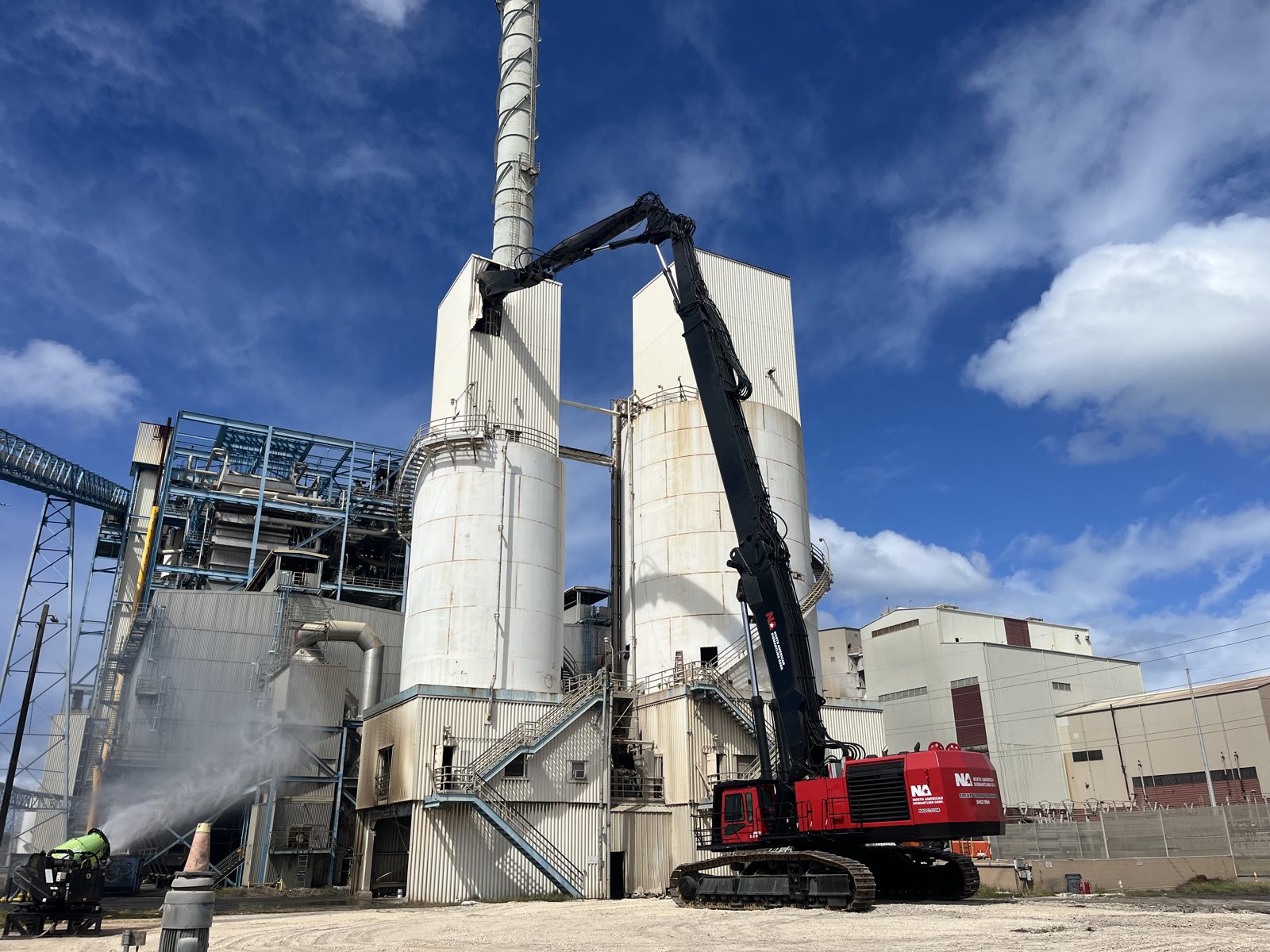 NADC high-reach excavator dismantling concrete silos with dust suppression in operation